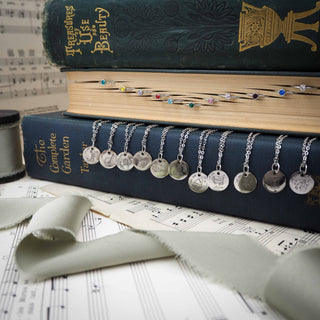 Necklaces with round pendants on a stack of books and music sheets