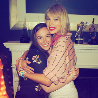 Two women, Holly Armstrong and Taylor Swift, hugging in front of a decorative fireplace with awards on a shelf. Nashville, TN August 2019.