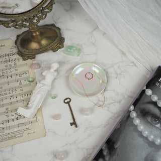 Decorative items on a marble surface including a key, small statue, and glass dish.